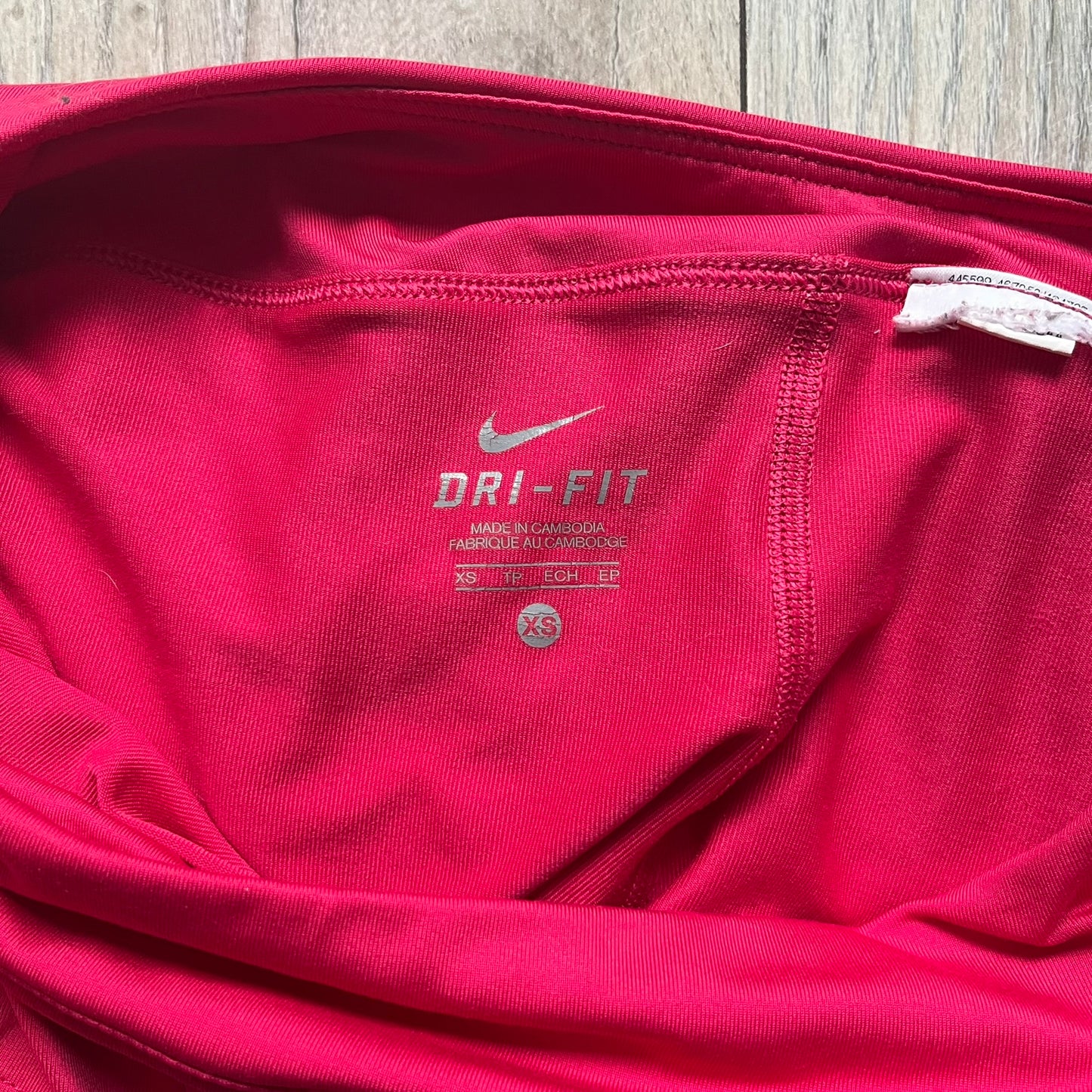 Nike Smash Classic Pink/Orange Tennis Skirt is a women’s tennis skort with built-in inner shorts. The design is constructed in three sections: a dark pink waistband and upper panel, an orange middle stripe, and a lower dark pink layer with two cutouts revealing orange fabric underneath. A white Nike Swoosh is placed at the lower hem, with a small Nike Court logo on the side.