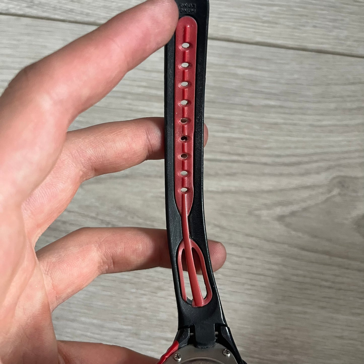 Hand holding a red and black belt with a wooden surface background