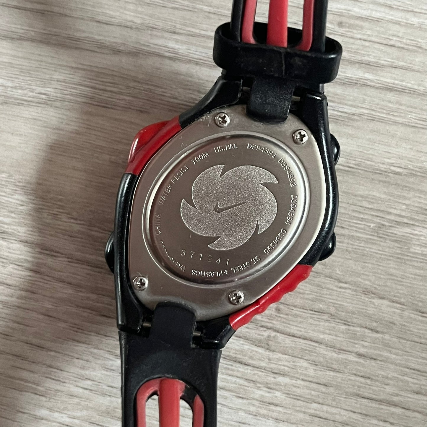 Close-up of a watch case with engraved design on a wooden surface