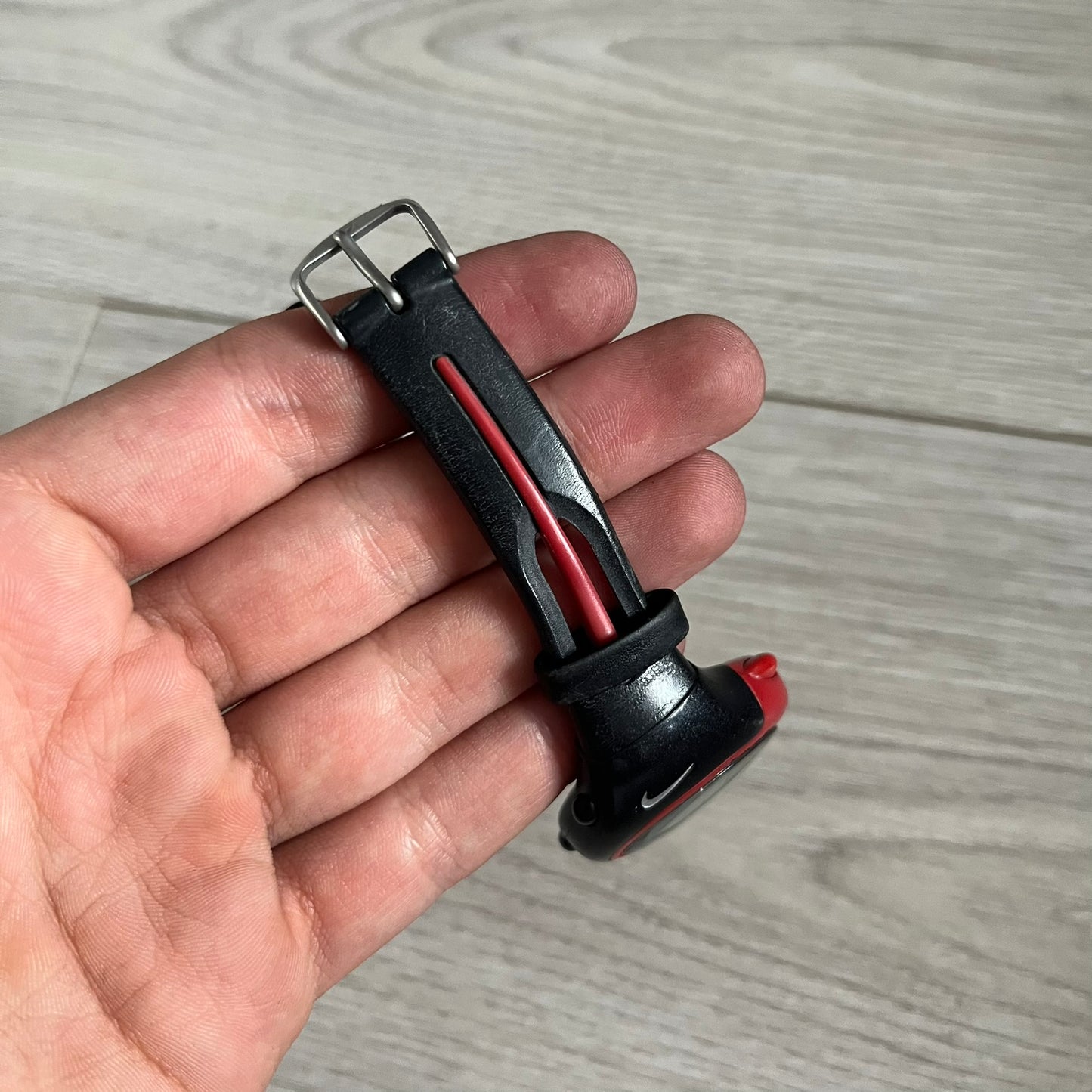 Black and red object held in a hand on a wooden surface
