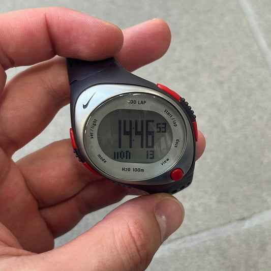 Nike Triax Speed 100 Regular Red Digital Watch features a silver-tone case with four red side buttons and a front button for the backlight function. The watch has an black Nike Swoosh on the top of the case, 100-lap memory, multiple modes, and 100m water resistance. It comes with brown-ish bracelet.