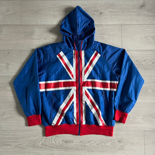 Nike UK Olympics 2008 Split Windbreaker designed by Jarrett Reynolds. Features a blue base with Union Jack-inspired red and white stripes on the front, representing Great Britain. Dual side zippers allow the jacket to be split in half and combined with other pieces from the collection, with a subtle United Kingdom flag inside the pocket.