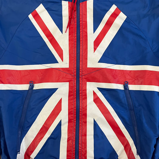 Nike UK Olympics 2008 Split Windbreaker designed by Jarrett Reynolds. Features a blue base with Union Jack-inspired red and white stripes on the front, representing Great Britain. Dual side zippers allow the jacket to be split in half and combined with other pieces from the collection, with a subtle United Kingdom flags inside the pocket.