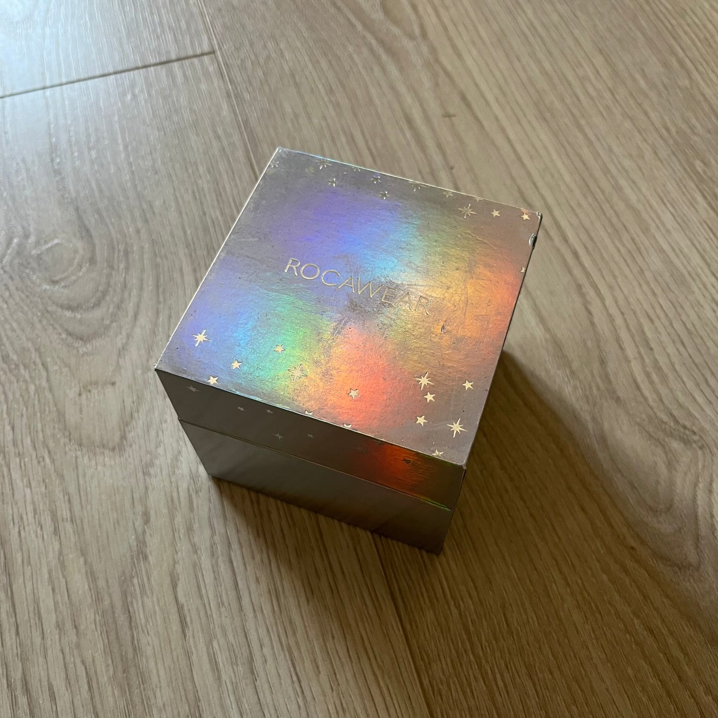 Set of four Rocawear bracelets, each with distinct design elements. Highlights include a “Girl Power” cube bracelet, a burgundy string with gold chain and pearl/zirconia charms, and two simple rose gold bands. Comes presented in a holographic silver box, ideal for collectors or as a stylish accessory set.
