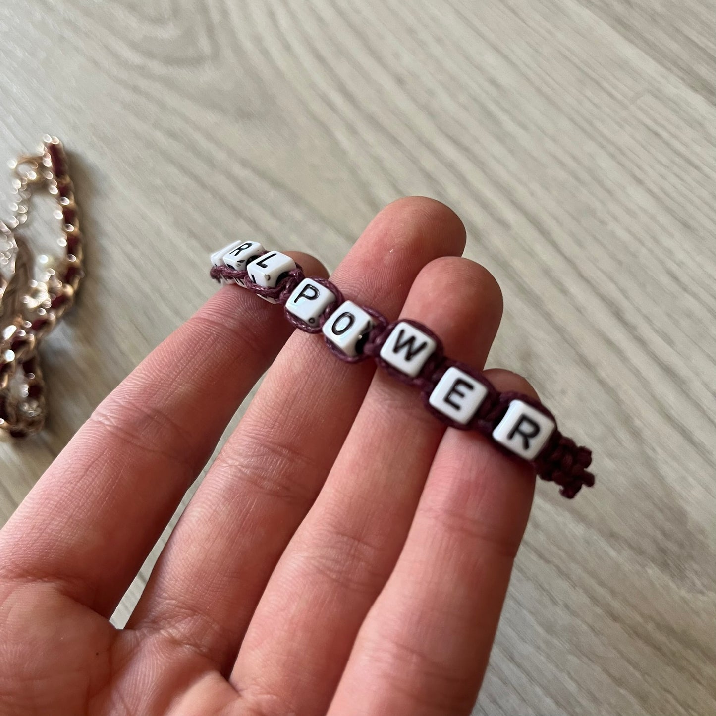 Set of four Rocawear bracelets, each with distinct design elements. Highlights include a “Girl Power” cube bracelet, a burgundy string with gold chain and pearl/zirconia charms, and two simple rose gold bands. Comes presented in a holographic silver box, ideal for collectors or as a stylish accessory set.