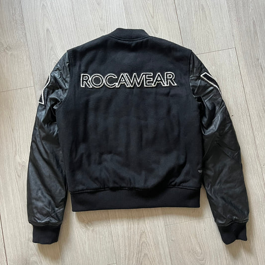 Rocawear black bomber jacket detailed with multiple statement patches, including “R” and “W” on the shoulders, a Rocawear logo with a “4” on the chest, and a large text logo across the back. Crafted with great detailing, it reflects the brand’s early 2000s streetwear identity.