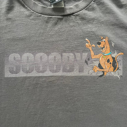 Gray Scooby-Doo tee from 1998, officially licensed by Warner Bros. Studio Store. Graphic shows Scooby emerging through the shirt as if he tore it, paired with classic text. Single-stitch USA-made construction adds authentic vintage charm.