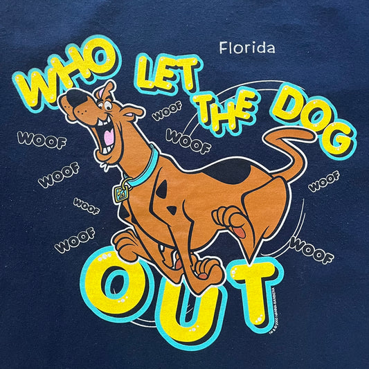 Vintage 2000 Scooby-Doo “Who Let The Dog Out” tee in Navy. Features a big colorful graphic of Scooby running, framed by “Who Let The Dog Out” and playful “Woof” prints. Licensed by Hanna-Barbera with the original green Scooby-Doo tag.