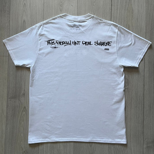 White Slawn Batpreme tee featuring a Batman-inspired graphic with iconic twist by Slawn and Supreme text overlay. Printed neck tag shows Slawn’s signature, while the back reads “This really isn’t real Supreme” in hand-drawn style with signature and logo. A striking, collectible streetwear piece.