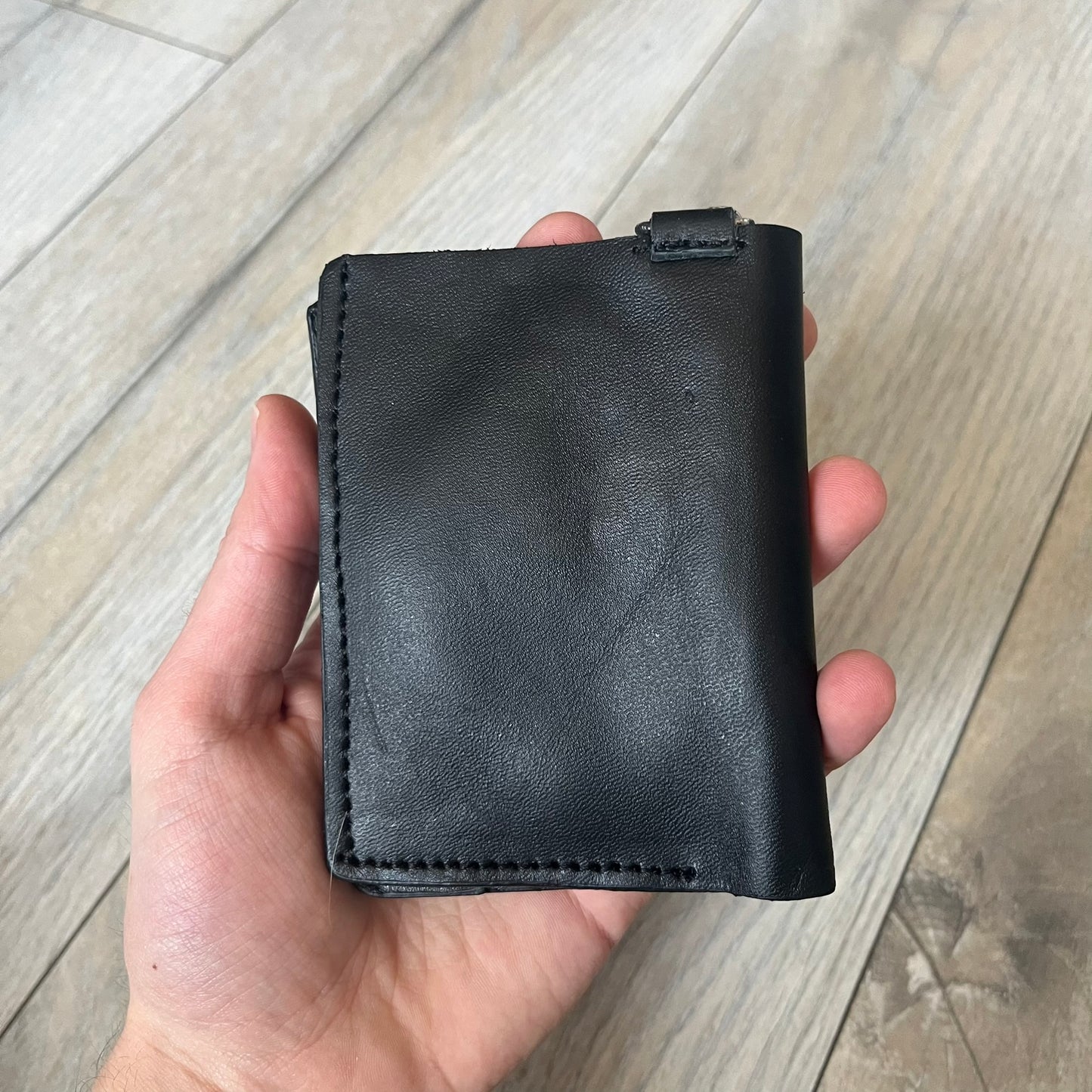 Slawn Leather Chain Man Wallet is a black foldable leather wallet featuring original artwork by Slawn on the front, depicting a red running figure holding a revolver and smoking a cigar. The wallet includes an attached metal chain for securing to clothing, along with eight card compartments and one top compartment for cash.