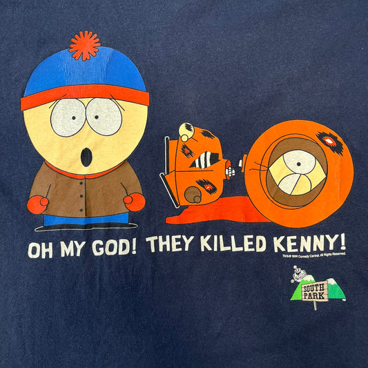 South Park 1998 “They Killed Kenny” Navy Tee features a a front graphic of Stan standing with a surprised expression next to a fallen Kenny. Below the characters is white “Oh My God! They Killed Kenny!” text, with a small South Park logo and 1998 licensing detail printed underneath on the right side. Made from cotton.