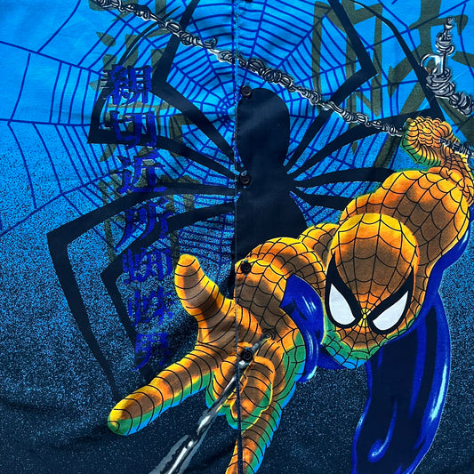 Blue Spider-Man button-up shirt featuring an all-over web print and mirrored graphics of Spider-Man shooting webs on both sides. Centered Spider-Man logo completes the great design. A striking, comic-inspired piece perfect for fans and collectors.