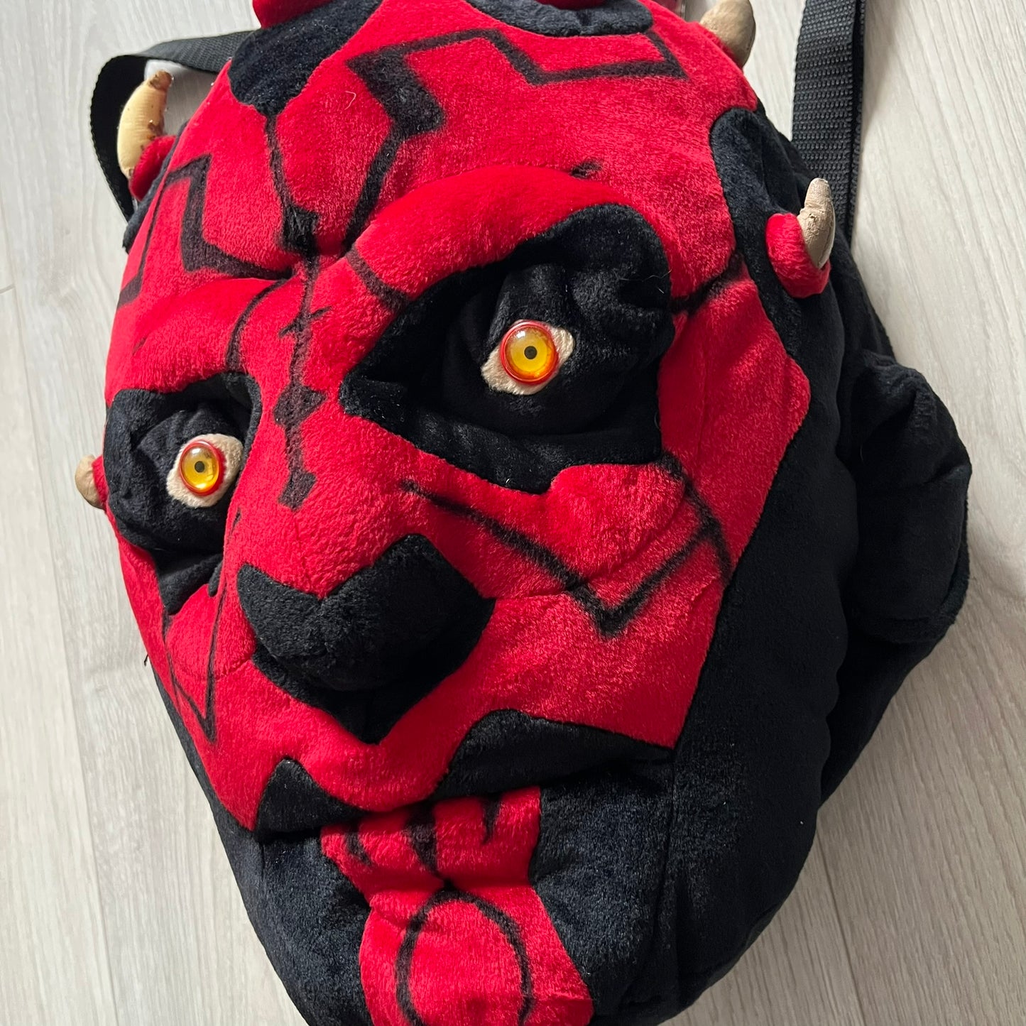 Star Wars 90's Darth Maul Head Backpack - a plush backpack shaped like Darth Maul’s head with striking red-and-black detailing and realistic plastic eyes. Features a small zip compartment on the back and adjustable straps, perfect as a collectible or standout accessory.