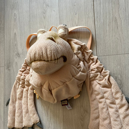 Vintage 1990s Star Wars backpack shaped like Jar Jar Binks’ head, complete with oversized ears for a playful, collectible design. This nostalgic piece captures the quirky charm of the character while offering functional storage. A rare, fun accessory for fans of classic Star Wars memorabilia.