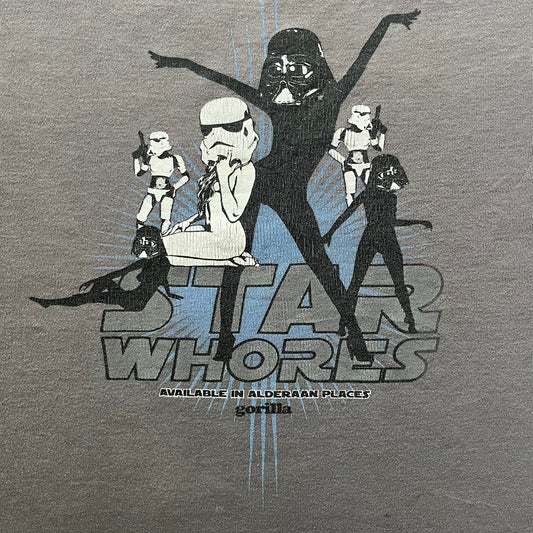 Gray Star Wh*res tee showcasing female figures in Stormtrooper and Vader masks. Logo sits prominently on the chest with witty “Available in Alderaan Places” tagline beneath. A perfect sci-fi parody tee.