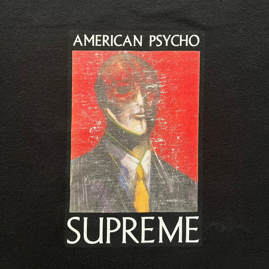 Supreme FW23 “American Psycho” tee in black, released October 2023. Features a large front print of Marshall Arisman’s iconic cover art for Bret Easton Ellis’s novel American Psycho, with big SUPREME text beneath. A standout graphic piece that merges literature, art, and streetwear.