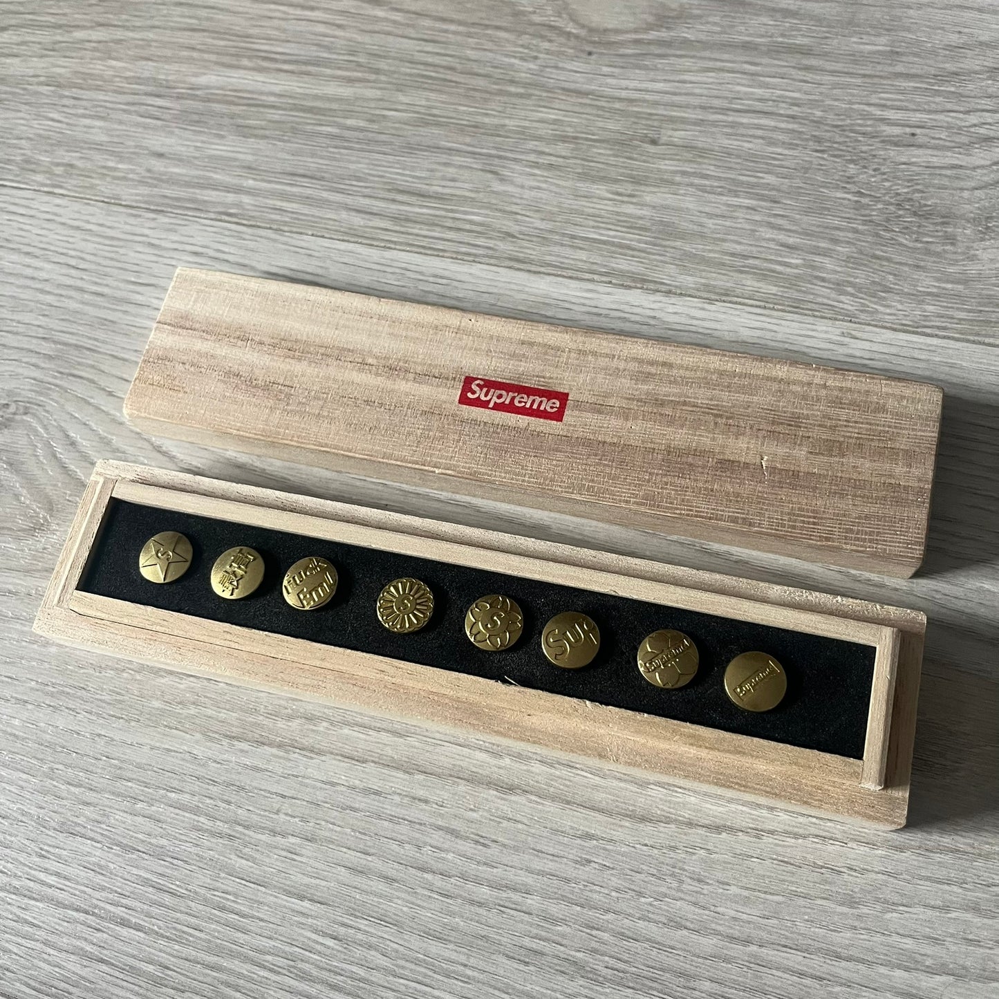 The Supreme CDW Push Pin FW24 Set, released in Week 10 (October 2024), offers eight brass-made pins with detailed debossed graphics including the classic Box Logo and “Fuck Em!” motif. Produced in Japan, this set turns simple desk essentials into collectible Supreme artifacts.