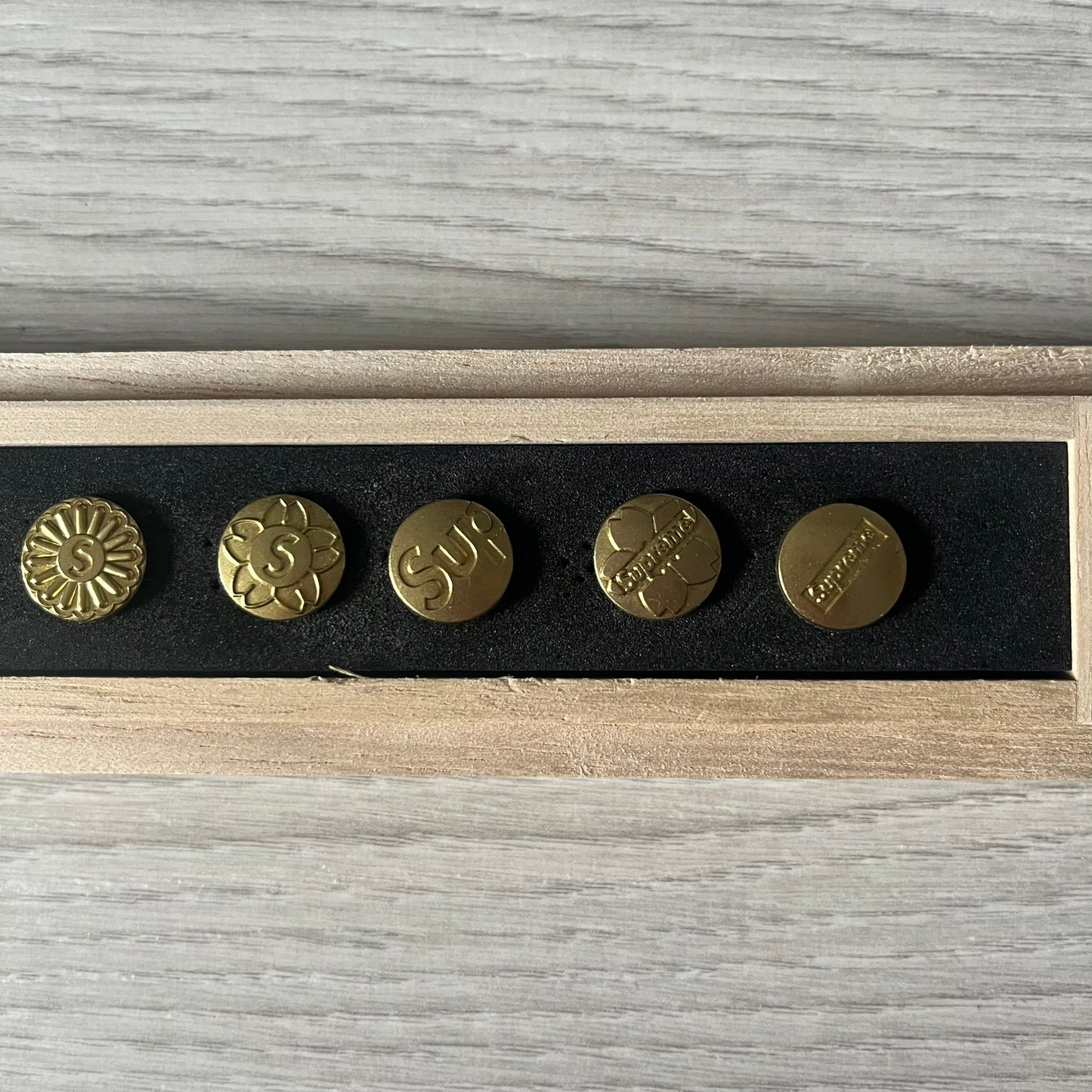 The Supreme CDW Push Pin FW24 Set, released in Week 10 (October 2024), offers eight brass-made pins with detailed debossed graphics including the classic Box Logo and “Fuck Em!” motif. Produced in Japan, this set turns simple desk essentials into collectible Supreme artifacts.