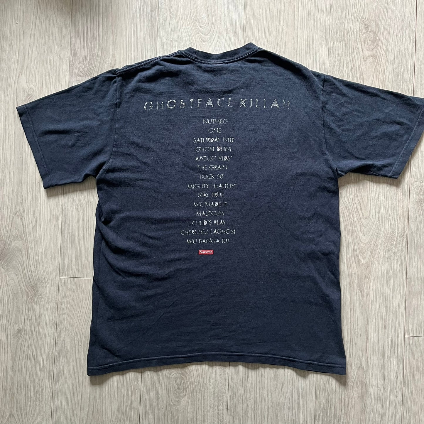 Supreme Clientele FW20 Navy Tee released in October 2020 as part of Supreme’s Fall/Winter 2020 collection. This cotton tee pays tribute to Ghostface Killah’s 2000 album Supreme Clientele, featuring the album’s iconic title graphic on the front and full tracklist on the back. A standout Supreme graphic tee that merges streetwear with hip-hop history.