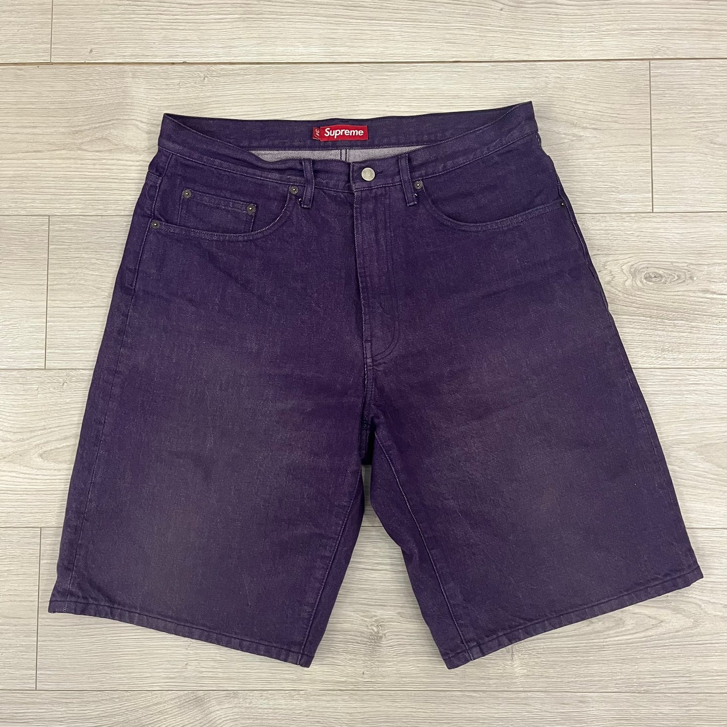 Supreme Denim Purple SS25 Baggy Shorts crafted from 13 oz. all-cotton denim in a purple hue. Features a relaxed baggy fit, classic five-pocket styling, zip fly, copper oxide rivets, and embroidered Supreme New York logo on the back pocket. Durable, stylish, and perfect for everyday streetwear.