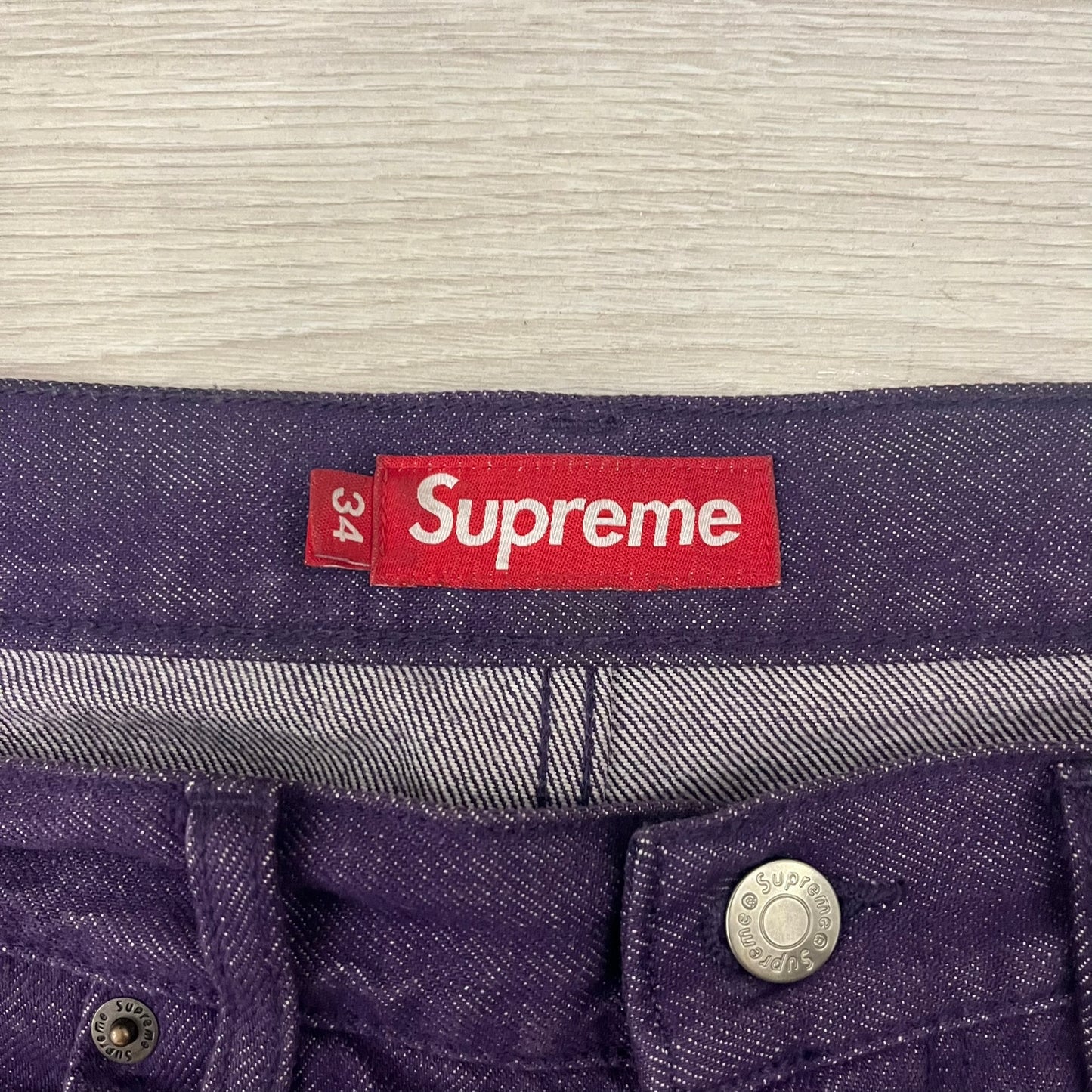 Supreme Denim Purple SS25 Baggy Shorts crafted from 13 oz. all-cotton denim in a purple hue. Features a relaxed baggy fit, classic five-pocket styling, zip fly, copper oxide rivets, and embroidered Supreme New York logo on the back pocket. Durable, stylish, and perfect for everyday streetwear.