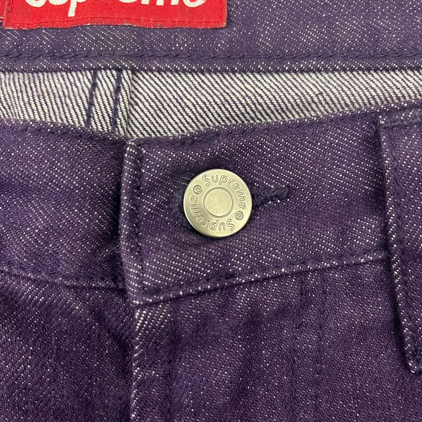 Supreme Denim Purple SS25 Baggy Shorts crafted from 13 oz. all-cotton denim in a purple hue. Features a relaxed baggy fit, classic five-pocket styling, zip fly, copper oxide rivets, and embroidered Supreme New York logo on the back pocket. Durable, stylish, and perfect for everyday streetwear.