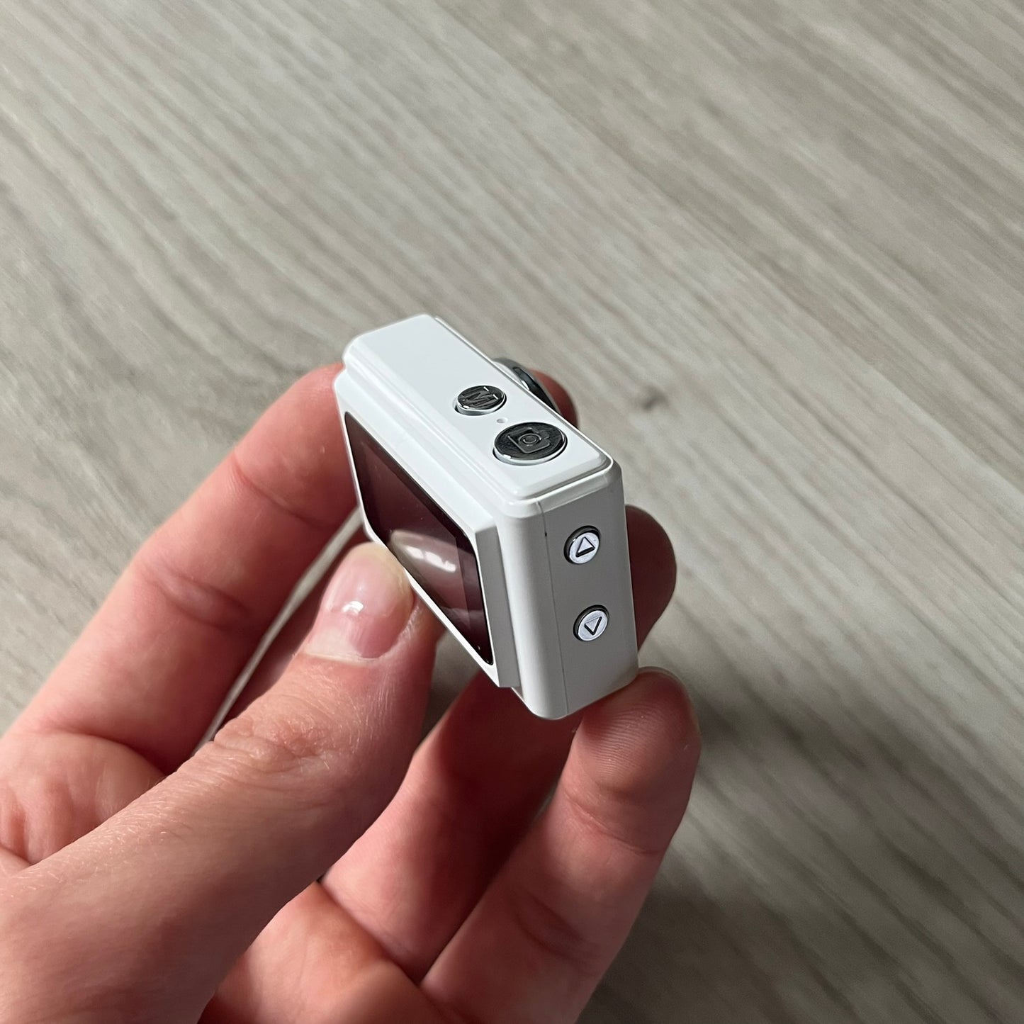 Supreme Digital Camera Keychain released for FW25 in white with a printed Supreme box logo on the front. This ultra-compact digital camera measures 1.92" x 1.14" x 1.1" and includes a 32GB TF card, USB-C cable, and built-in 1080p HD recording. When powered on, the screen displays the Supreme logo, with selectable interface colors in colors like: pink, green, or blue.