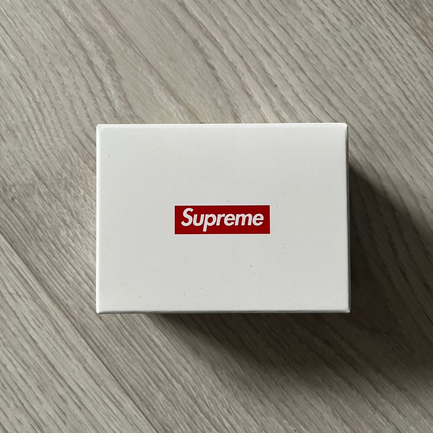 Supreme Digital Camera Keychain released for FW25 in white with a printed Supreme box logo on the front. This ultra-compact digital camera measures 1.92" x 1.14" x 1.1" and includes a 32GB TF card, USB-C cable, and built-in 1080p HD recording. When powered on, the screen displays the Supreme logo, with selectable interface colors in colors like: pink, green, or blue.