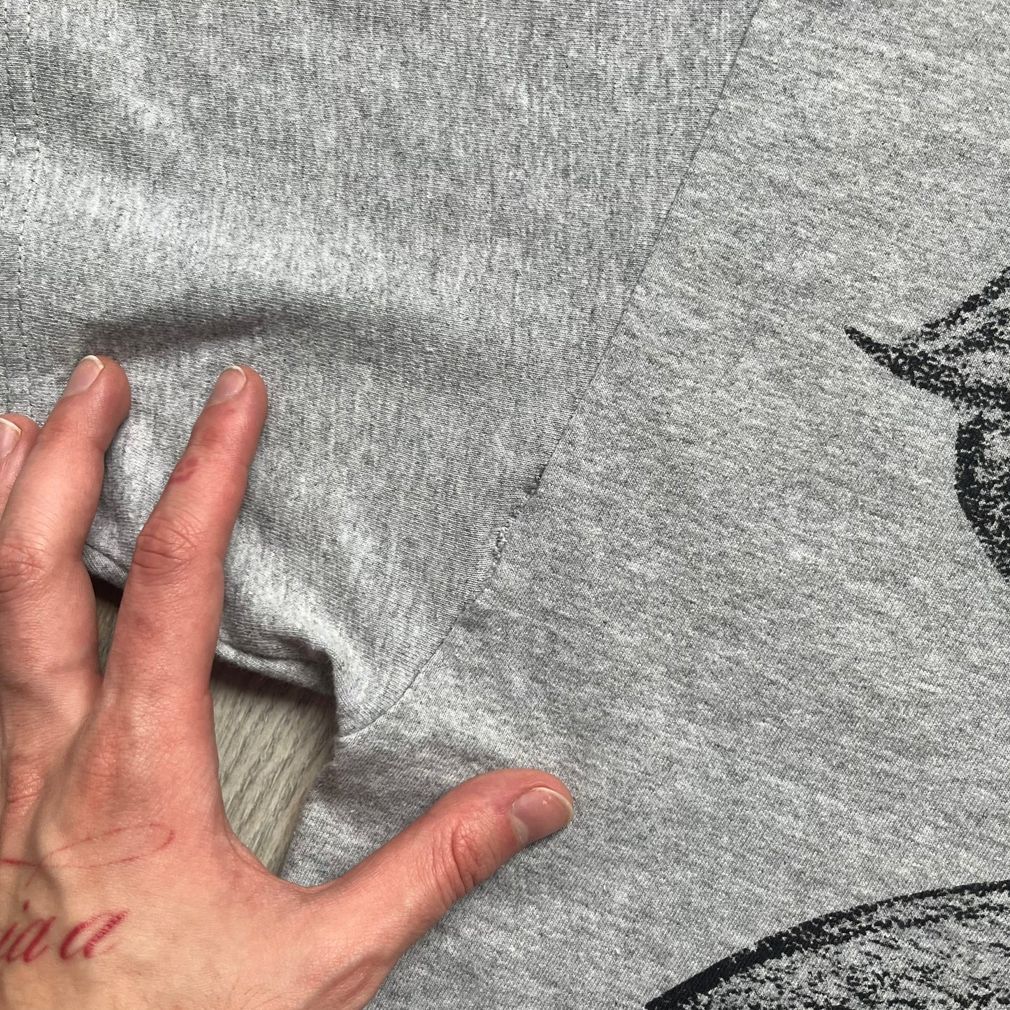 Supreme FW07 WTAPS “Live To Ride, Ride To Live” Gray Tee is a gray short-sleeve T-shirt released in Autumn/Winter 2007. The front features a black sketch of Robin on a skateboard with a small red Supreme logo beside it, while the upper back displays bold “Live To Ride, Ride To Live” text. The T-shirt was designed by Tetsu Nishiyama (WTAPS).