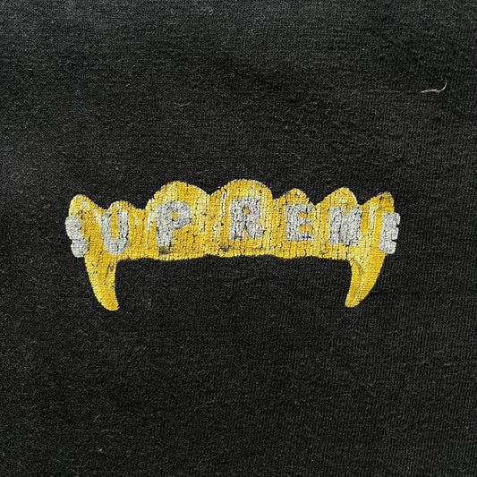 Supreme Fronts SS19 Black Tee released on February 21, 2019, as part of the brand’s Spring/Summer 2019 collection. Crafted from 100% cotton, it features a gold grill design with diamond fangs and a jeweled Supreme logo across the teeth. A standout graphic tee from Supreme’s early SS19 lineup.