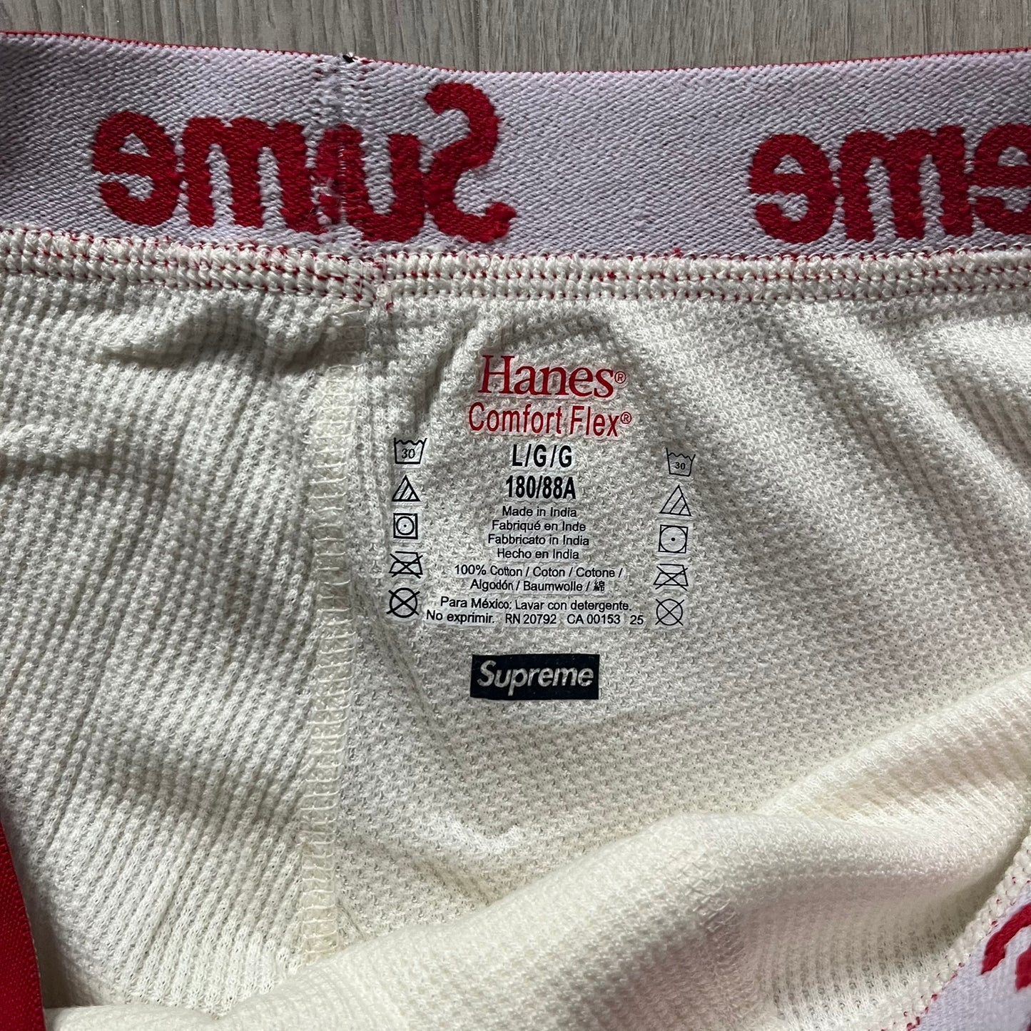 Supreme Hanes Bones Thermal Pant FW25 in natural/white, crafted from 100% cotton. Features black skeletal bone prints running down both legs and a red elastic waistband with white Supreme branding throughout. Released October 23, 2025.