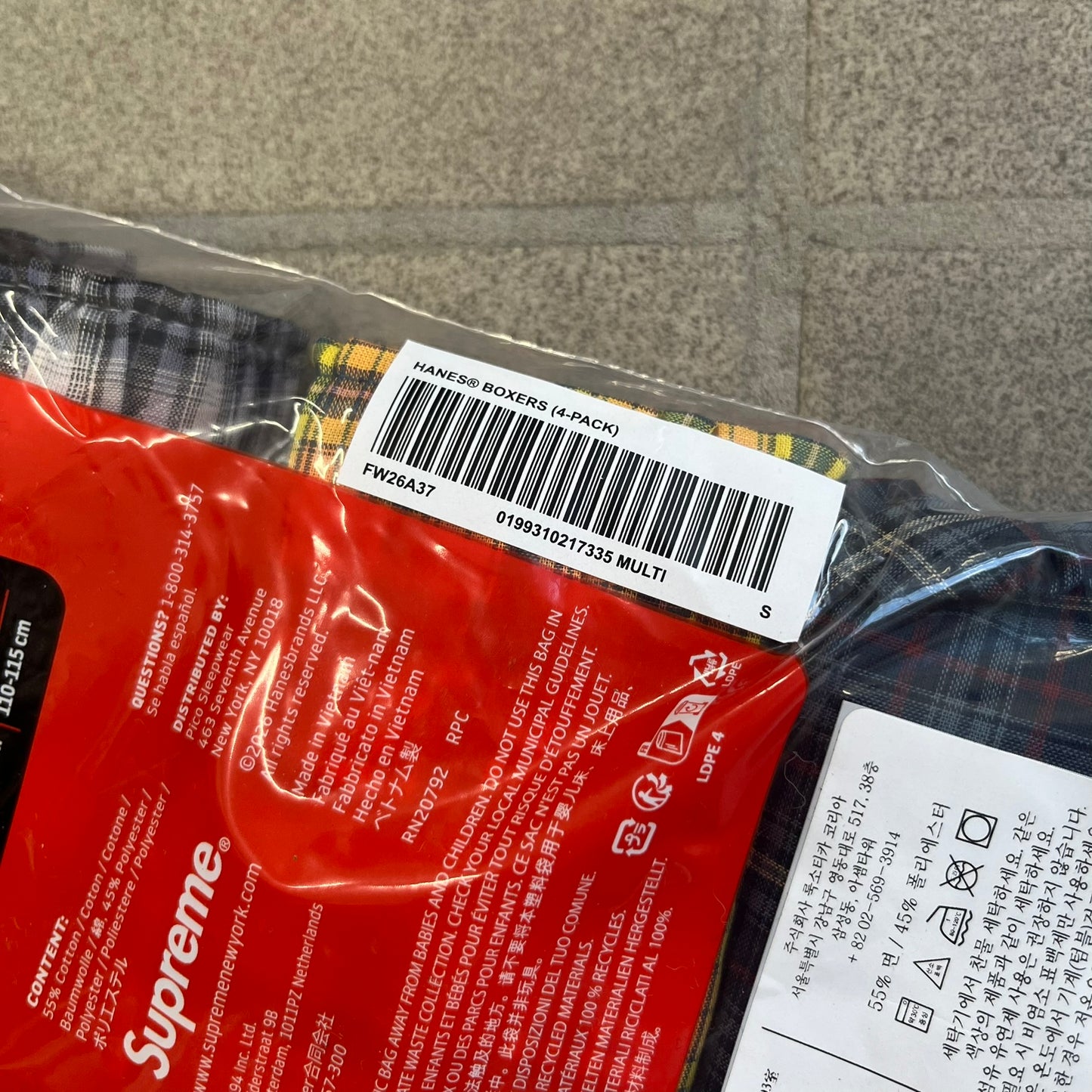 Supreme Hanes FW26 Plaid Boxers feature a plaid pattern and a red Supreme elastic waistband concealed inside. Made from 55% cotton and 45% polyester with Hanes Comfort Flex construction. Pink, grey, blue, and yellow colorways.