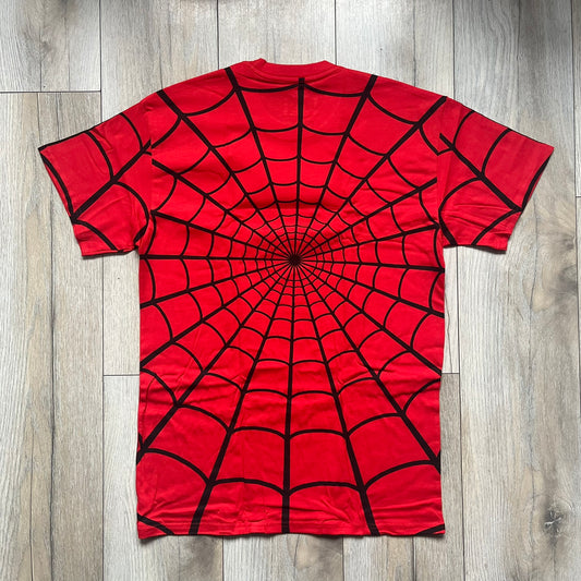 Supreme Hanes SS26 Spider-Man Red Tagless Tee is a red all-cotton crewneck T-shirt from the Spring/Summer 2026 collection, produced on a Hanes tagless blank. The shirt features an all-over black web print covering the front, back, and sleeves, with a small red Supreme stamp logo printed near the bottom corner.