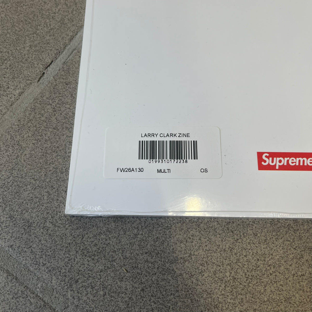 Supreme Larry Clark FW26 Multicolor Zine is a 48-page white zine with original photography by Larry Clark, including a poster insert. The cover features Gabbriette (Gabriella Leigh Bechtel) styled in Supreme underwear against a USA flag backdrop, with hand-drawn "Supreme" text scribbled at the top and "Larry Clark" with a star at the bottom, while the back displays a small Supreme logo.