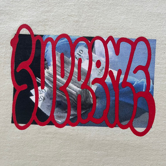 Natural Supreme tee from the FW23 season showcasing the “Payment” design. The front graphic depicts a pile of GBP banknotes with a large red graffiti-style Supreme tag layered across. A clean and minimalistic yet striking piece from the collection.