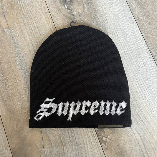 Supreme SS26 New Era Ghostface Black Beanie is a black knit beanie released on March 26, 2026, as part of the Spring/Summer 2026 collection. The front features a white Ghostface graphic, while the back includes “Supreme” text in a gothic-style font, with a small New Era logo embroidered on the side. The beanie is constructed from knit fabric for warmth and everyday wear.