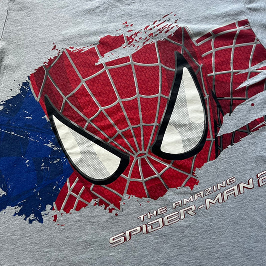 Gray 2014 Marvel tee featuring The Amazing Spider-Man 2 design with a “ripped page” effect showcasing Spider-Man’s face in the center. Text logo sits beneath the graphic for a bold cinematic touch. A collectible piece from the official movie merchandise line.