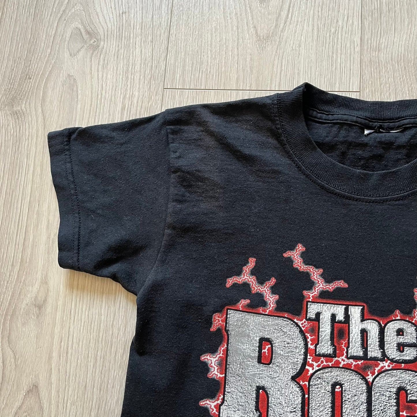 The Rock “Most Electrifying Man” 2000 Tee is a vintage WWE shirt featuring bold metallic-textured lettering with red lightning accents. The front proudly displays “The Rock,” while the back proclaims “The Most Electrifying Man in Sports Entertainment.” Licensed by World Wrestling Federation (WWF), this 2000 release is a must-have collectible for wrestling fans!