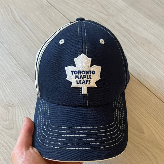 Navy blue cap with Toronto Maple Leafs logo on a wooden surface