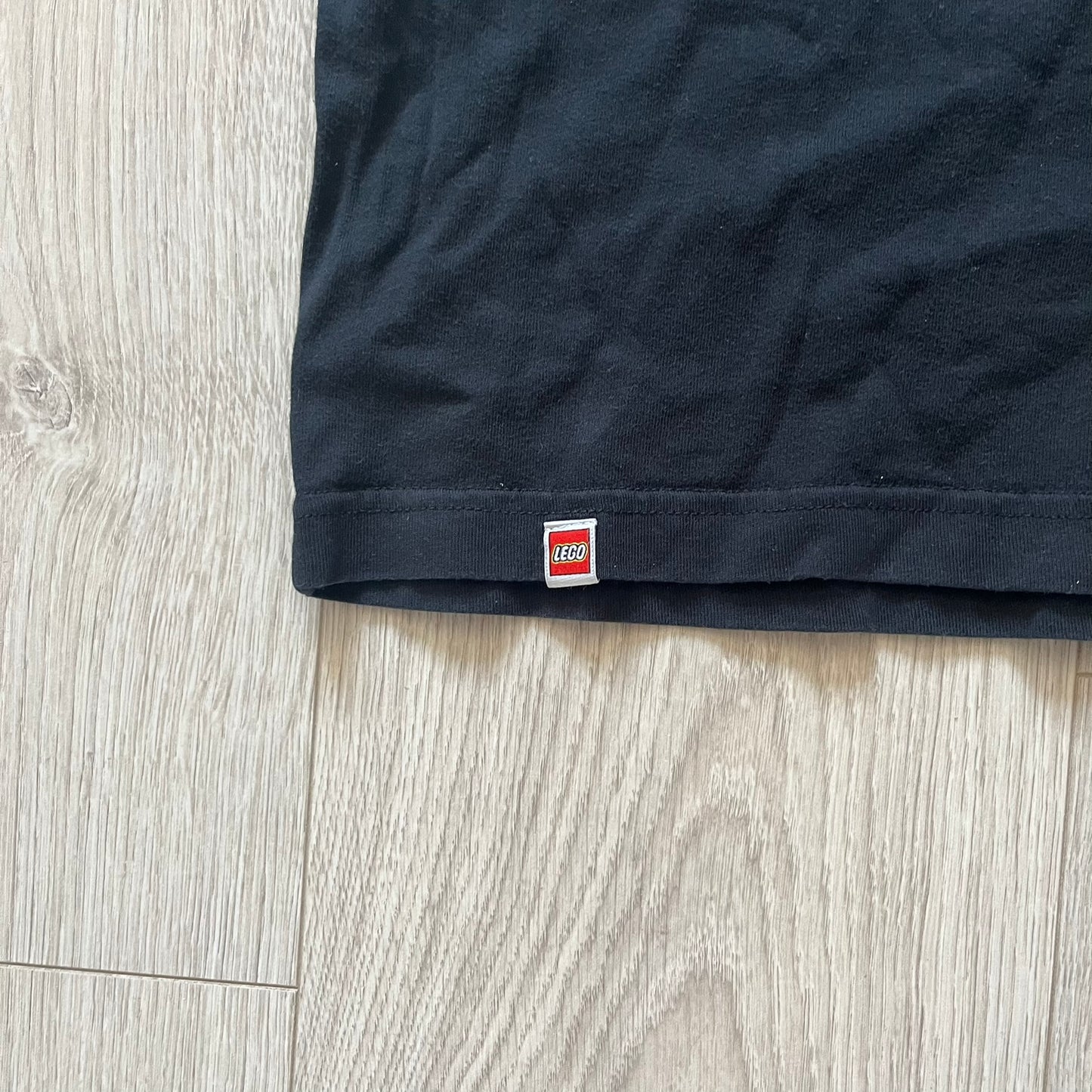 Black t-shirt with a LEGO logo tag on a wooden surface
