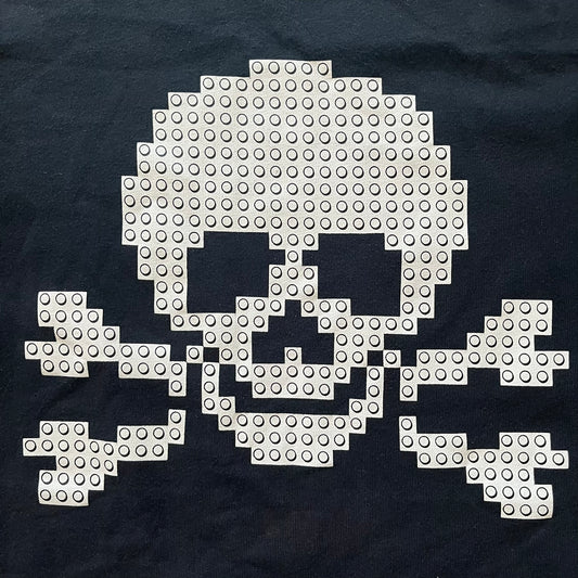 Pixelated skull and crossbones design made with building blocks on a dark fabric background