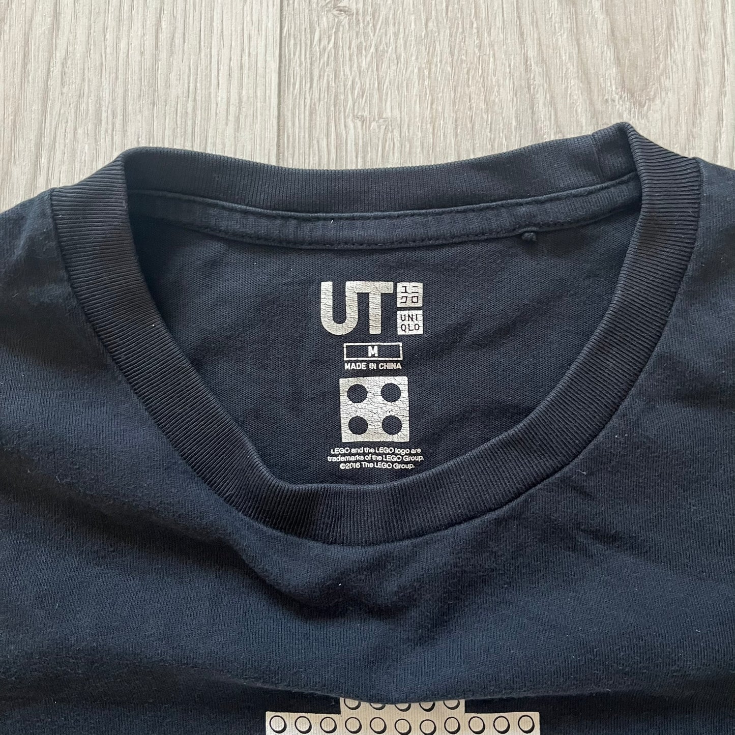 Close-up of a navy blue shirt with a brand label on a light wooden surface