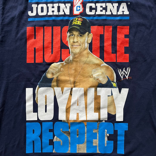 WWE John Cena “Hustle Loyalty Respect” Tee in navy, printed on a classic Screen Stars blank. Features a large front graphic of John Cena with big red, white, and blue lettering behind / in front of him and the WWE logo beside. A staple piece from Cena’s prime wrestling era.