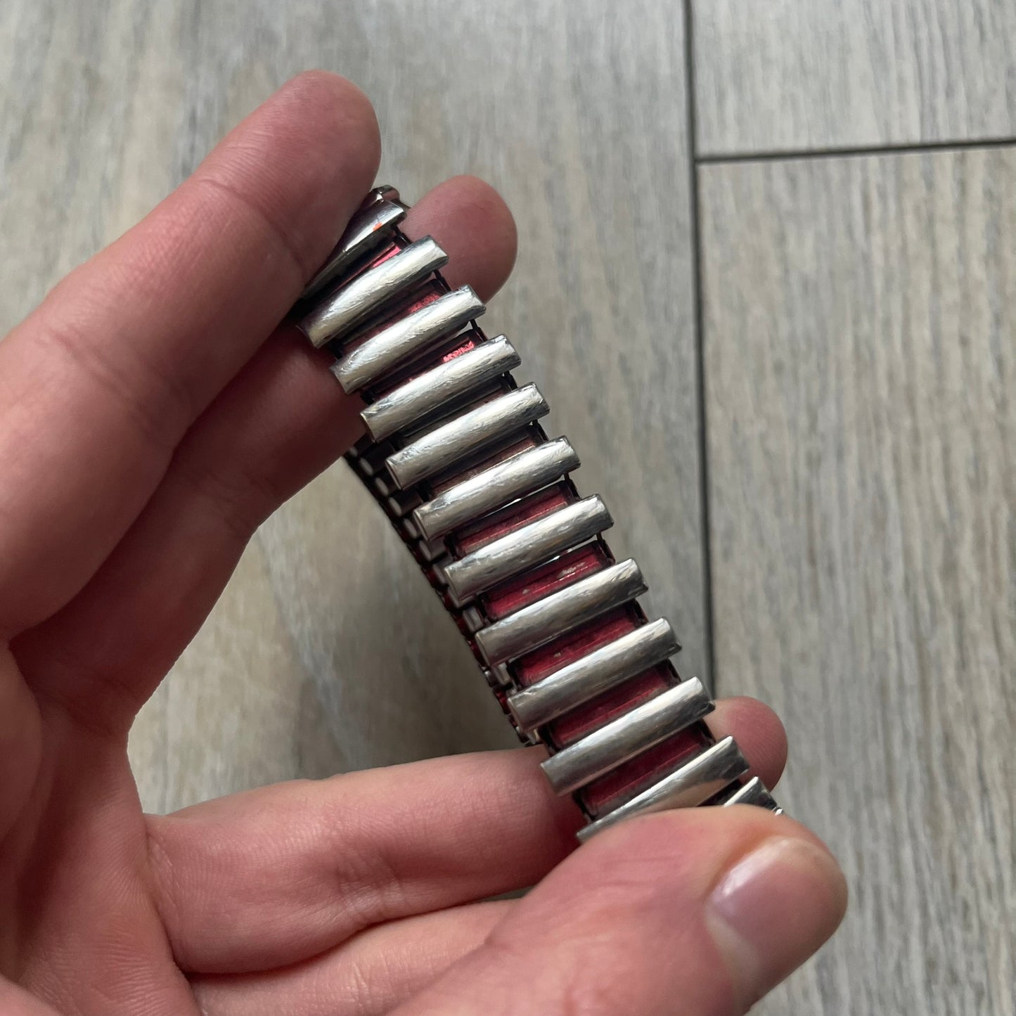 Warner Bros Tweety 1996 Analog Watch is a stainless steel watch with a stretch expansion bracelet made from connected metal links instead of a clasp. The watch features a reflective metallic dial with pink numerals and a graphic of Tweety alongside the phrase “I tawt I taw a puddy tat” in pink text. The caseback includes Warner Bros 1996 licensing.