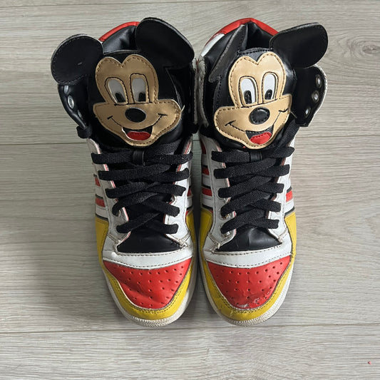 Pair of sneakers with Mickey Mouse design on a wooden surface