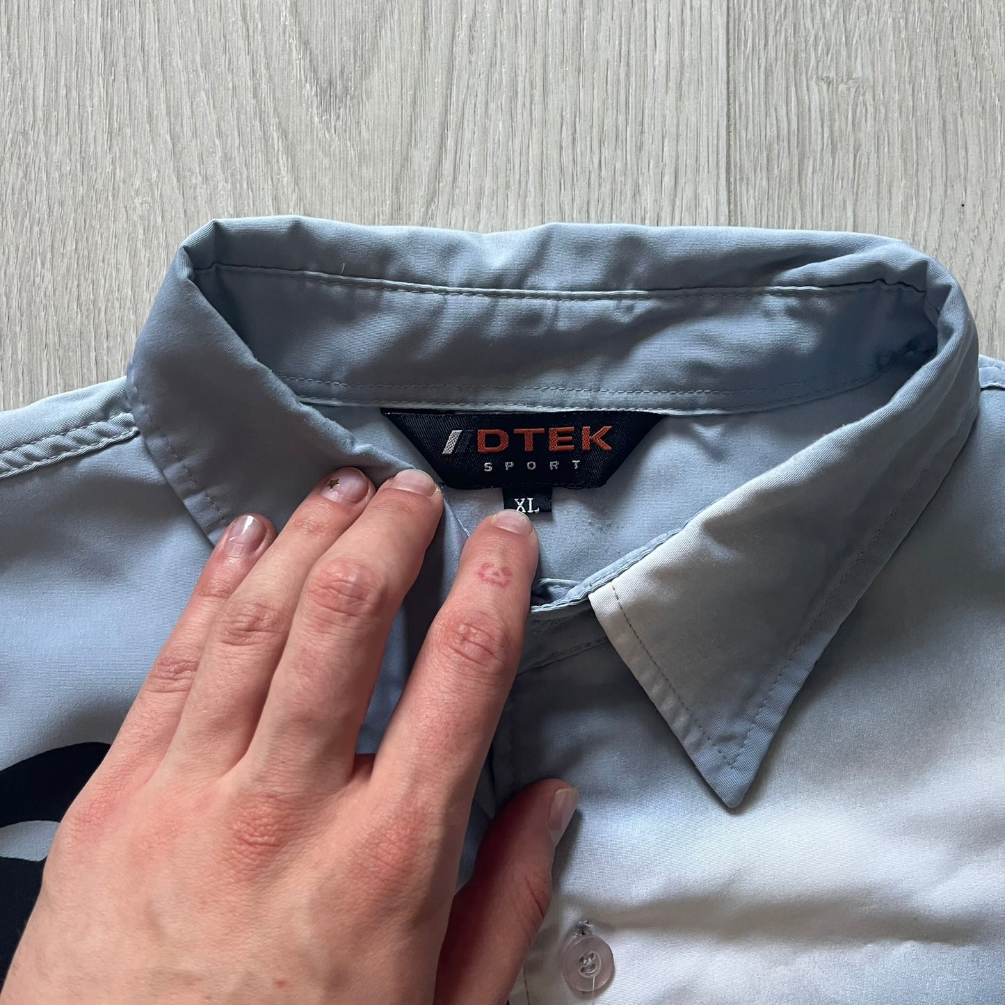 Light blue shirt with a visible brand label on a wooden surface