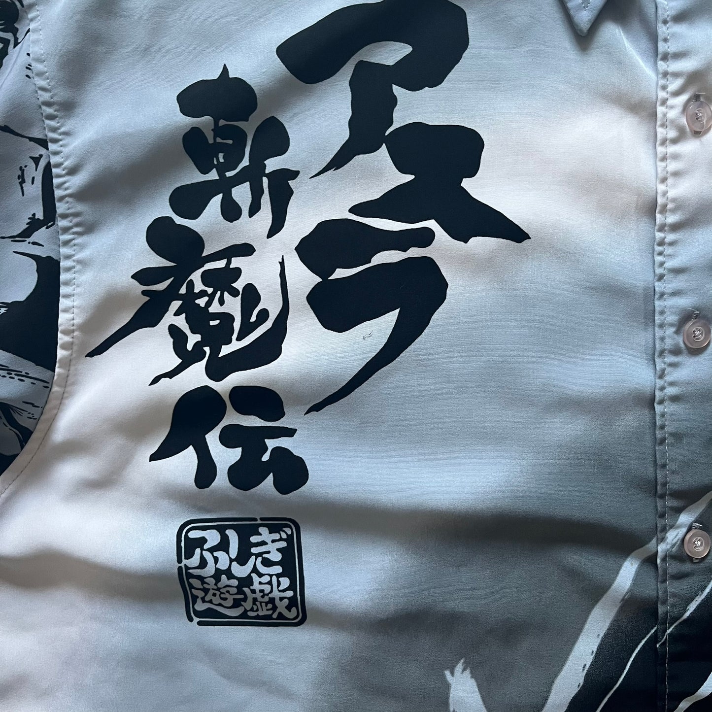 White shirt with black Japanese text and logo on a light gray background