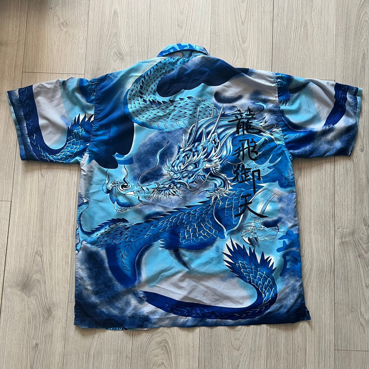 T-shirt with a blue dragon design on a wooden floor