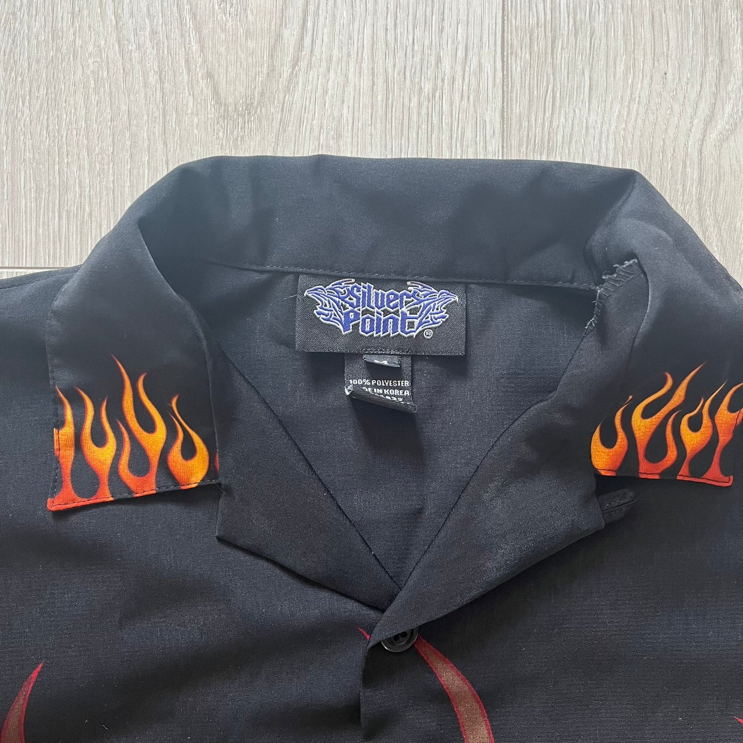 Black shirt with flame designs on sleeves and a visible brand label.