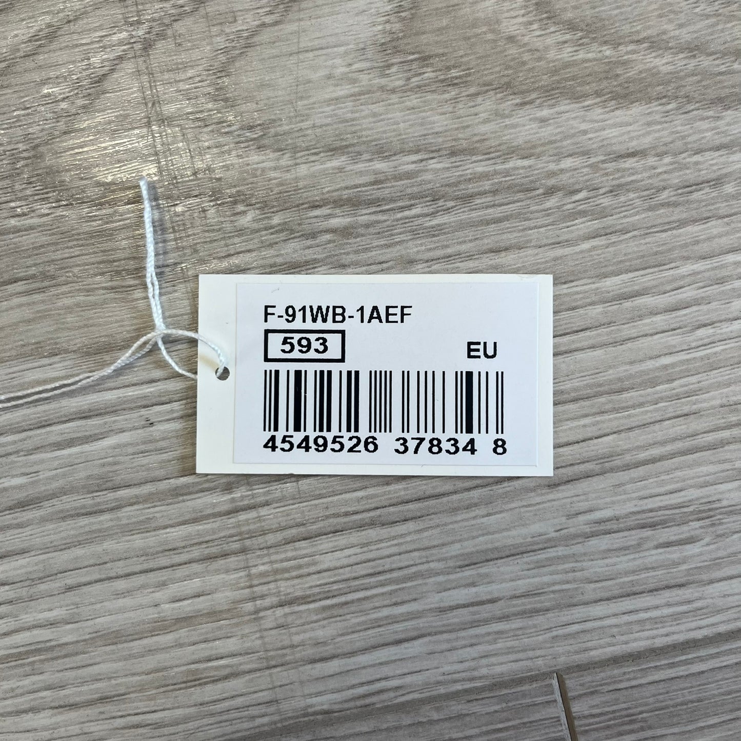 White tag with text and barcode on a wooden surface
